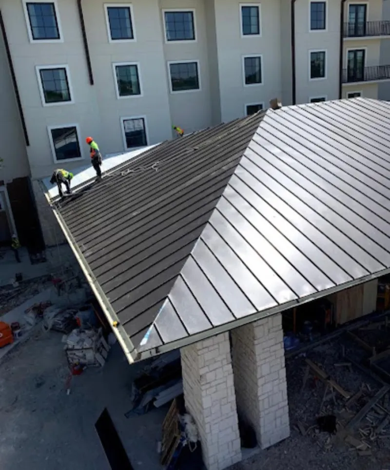 Crew installing standing seam metal roof panels on a commercial project in Swainsboro